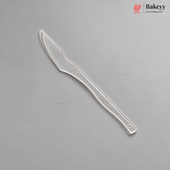 A single silver-colored plastic knife or spatula with a serrated blade and a long handle, shown diagonally on a solid gray background. The Bakeyy brand logo is visible in the top right corner.