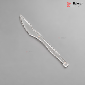 A single silver-colored plastic knife or spatula with a serrated blade and a long handle, shown diagonally on a solid gray background. The Bakeyy brand logo is visible in the top right corner.