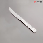 A white plastic serving knife with a serrated blade, shown diagonally on a neutral gray background with Bakeyy branding.