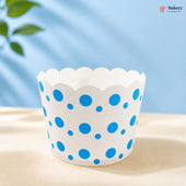 White cupcake liner with blue polka dots on a light surface with a blue background