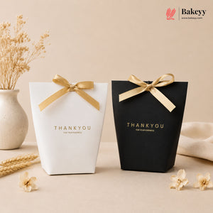 Two gift boxes, one white and one black, with gold ribbons and 'THANKYOU' text on a beige background.