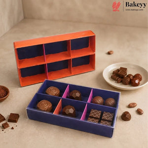 Chocolate gift box set from Bakeyy, featuring an orange and navy blue multi-compartment box shown both open and closed, filled with assorted milk and dark chocolates, alongside a small plate of chocolates on a beige background.