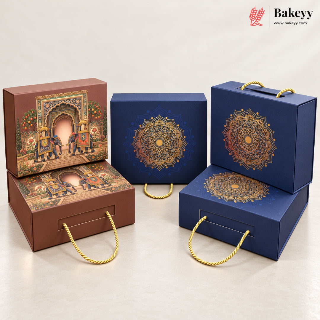 A set of decorative bakery gift boxes from Bakeyy, including two brown boxes with traditional Indian-style arch illustrations and handles, two navy blue boxes with gold mandala designs, and one matching navy box stacked on top of another. The boxes are arranged on a light beige studio background.