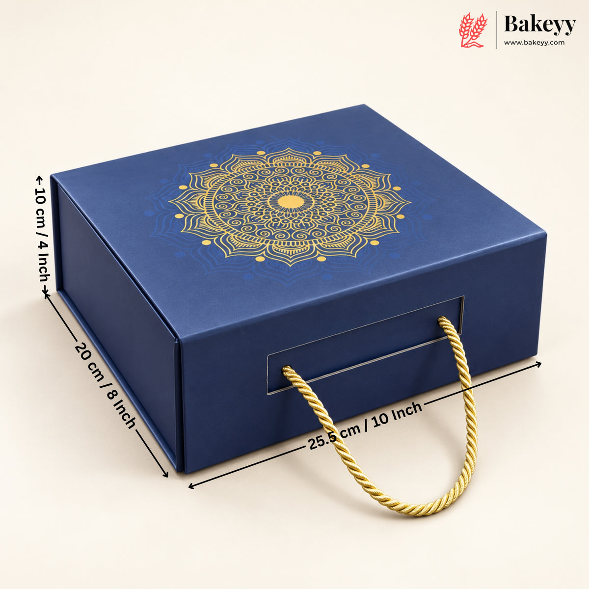 A dark blue square gift box with a gold mandala design on the lid and a gold rope handle, shown on a light beige background with dimension lines indicating 25.5 cm length, 10 cm height, and 20 cm width.