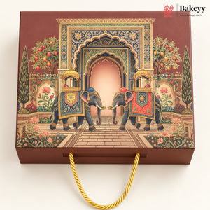 A rectangular brown gift box with a gold rope handle, decorated with an intricate traditional illustration of two decorated elephants under an ornate archway. The Bakeyy logo is visible in the top right corner.