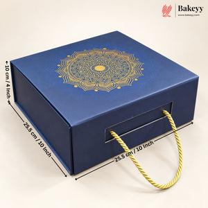 A blue rectangular bakery gift box with a gold mandala design on the lid, shown on a light beige background with dimension lines and text indicating measurements. The box has a front handle cutout with a gold rope handle and a Bakeyy logo watermark in the top right corner.