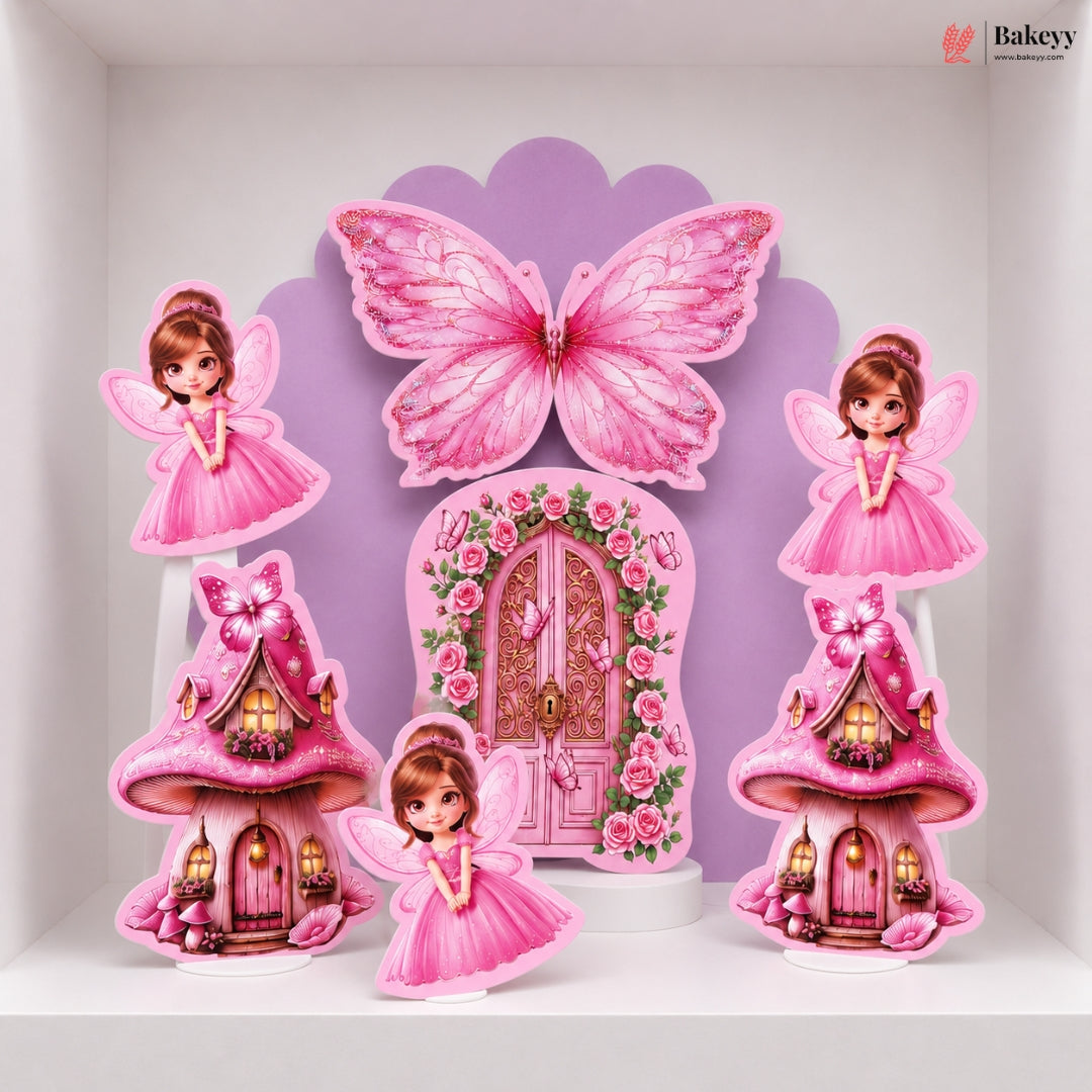 A set of pink fairy-themed party decorations displayed on a white shelf, including a large butterfly, a floral fairy door, two mushroom houses, and two fairy cutouts.
