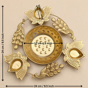 Gold-toned brass Diya holder with peacock and lotus motifs, shown with dimension markings indicating a height and width of 24 cm (9.5 inches) and a central diameter of 12 cm (4.