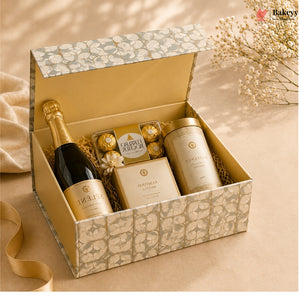 Gift box with champagne, cookies, and a candle on a beige surface