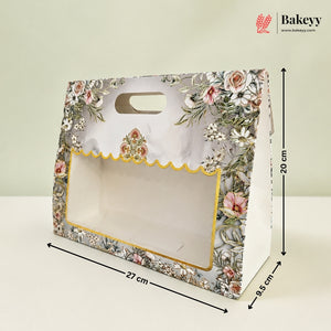 A floral bakery gift box with a clear window and scalloped gold trim, shown with dimension lines indicating 27 cm length, 20 cm height, and 9.5 cm width on a light background.