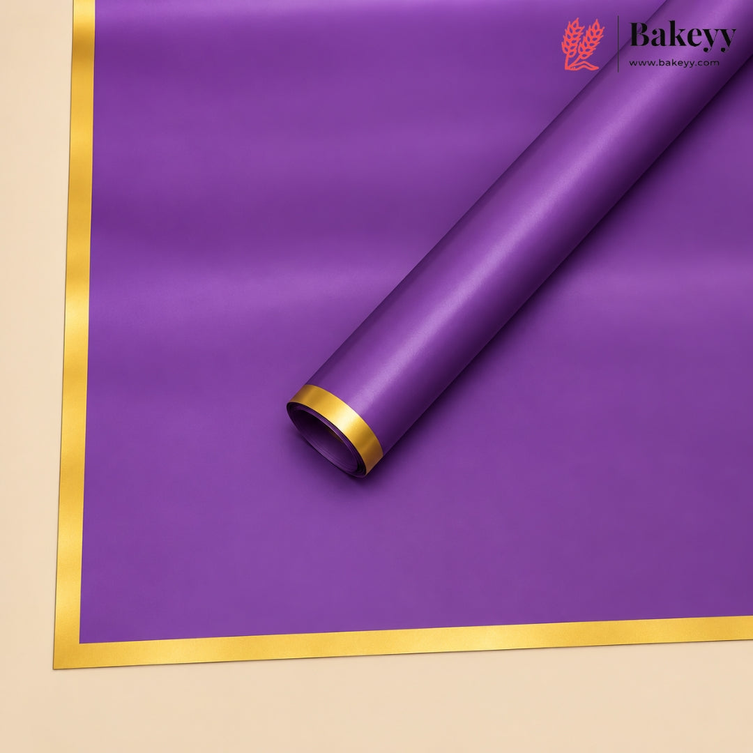A roll of purple bakery wrapping paper with a metallic gold border, shown partially unrolled on a light beige background. The Bakeyy brand logo is visible in the top right corner.