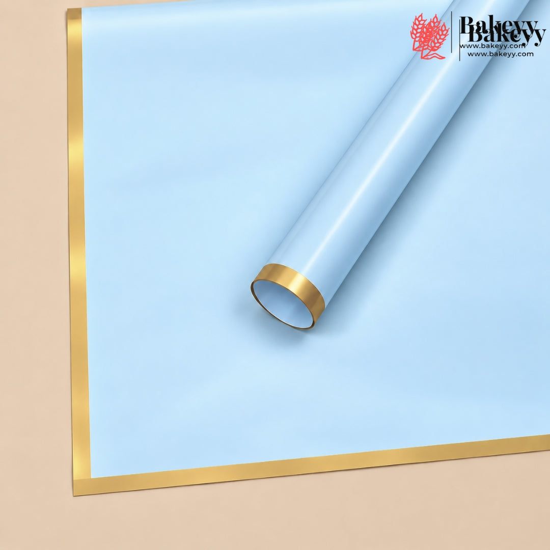 A roll of light blue bakery backdrop paper with metallic gold borders, shown partially unrolled on a beige background. The Bakeey brand logo is visible in the top right corner.