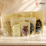 Set of clear stand-up pouches with different contents on a light surface, featuring the brand 'Bakeyy'.