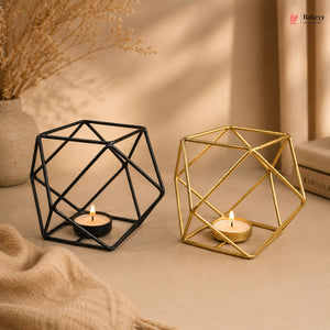 Geometric candle holders, one black and one gold, on a neutral background with candles inside.