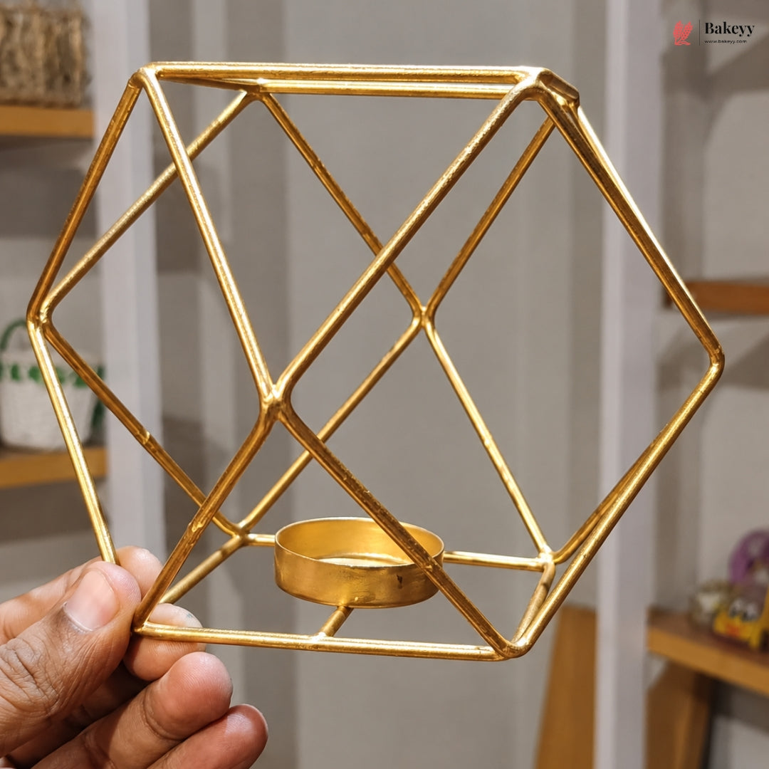 Gold geometric candle holder held by a hand with a blurred indoor background