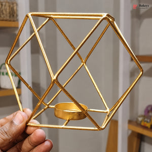 Gold geometric candle holder held by a hand with a blurred indoor background