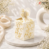 Decorative white box with gold patterns on a marble surface with flowers.
