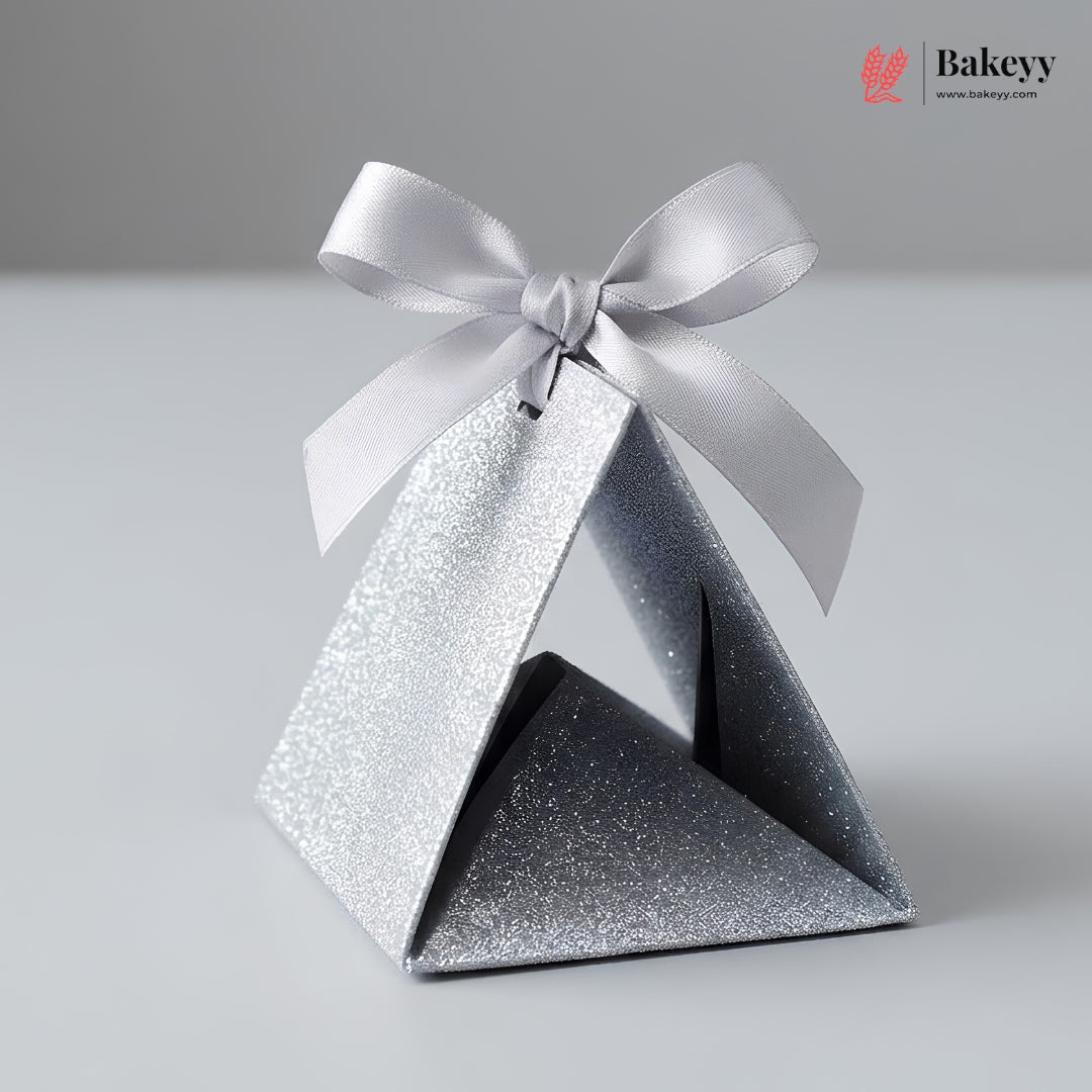 Silver glittery pyramid-shaped gift box with a white ribbon on a gray background, featuring the Bakeyy brand.