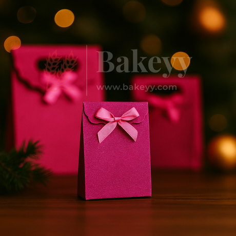 Pink gift bag with a bow on a wooden surface with blurred lights in the background