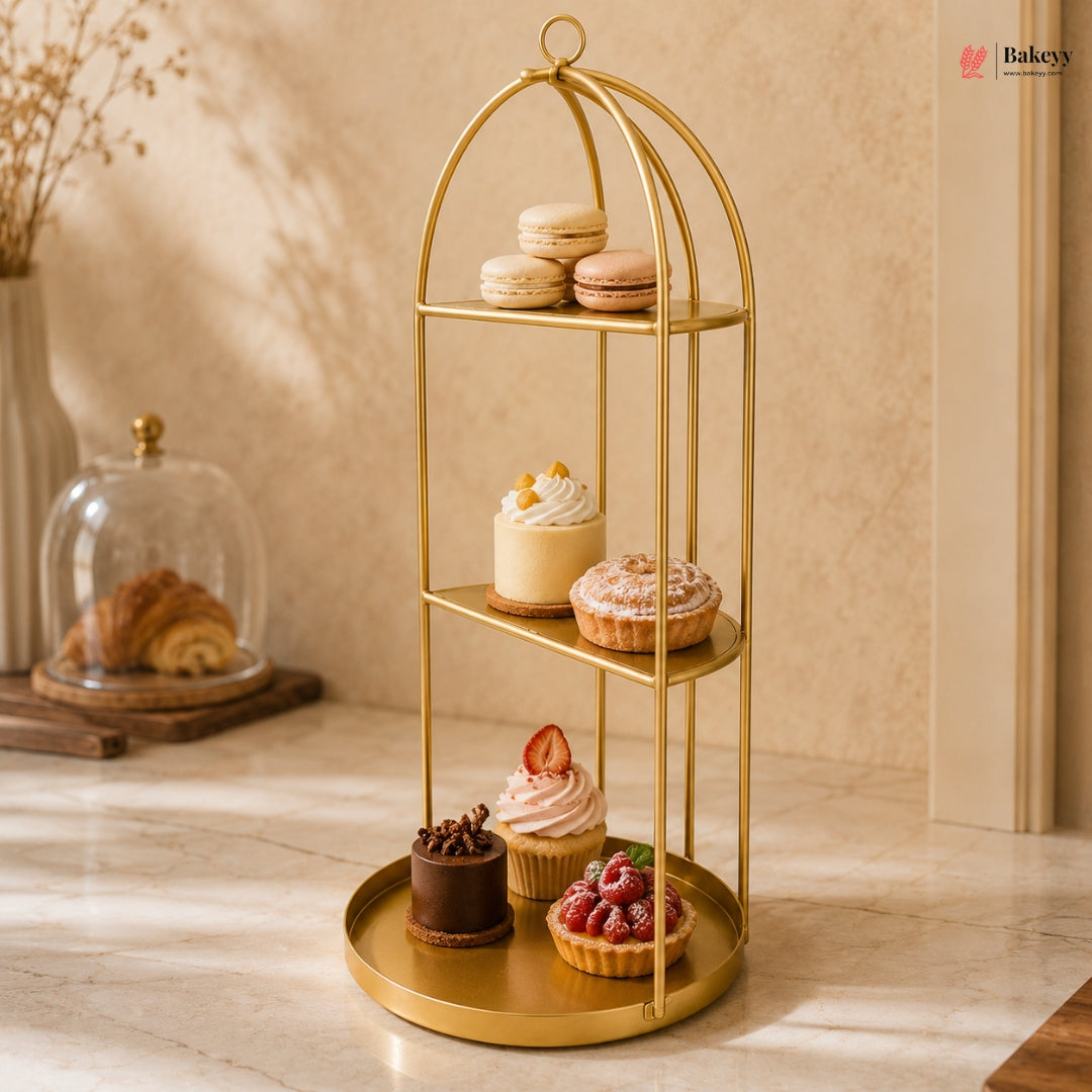 Gold three-tiered dessert stand with various pastries on a wooden surface.