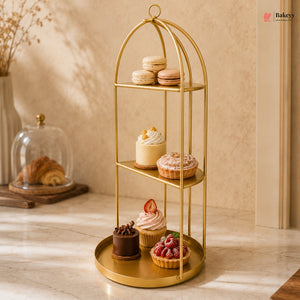Gold three-tiered dessert stand with various pastries on a wooden surface.