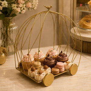 Decorative gold birdcage with cupcakes and macarons on a table.