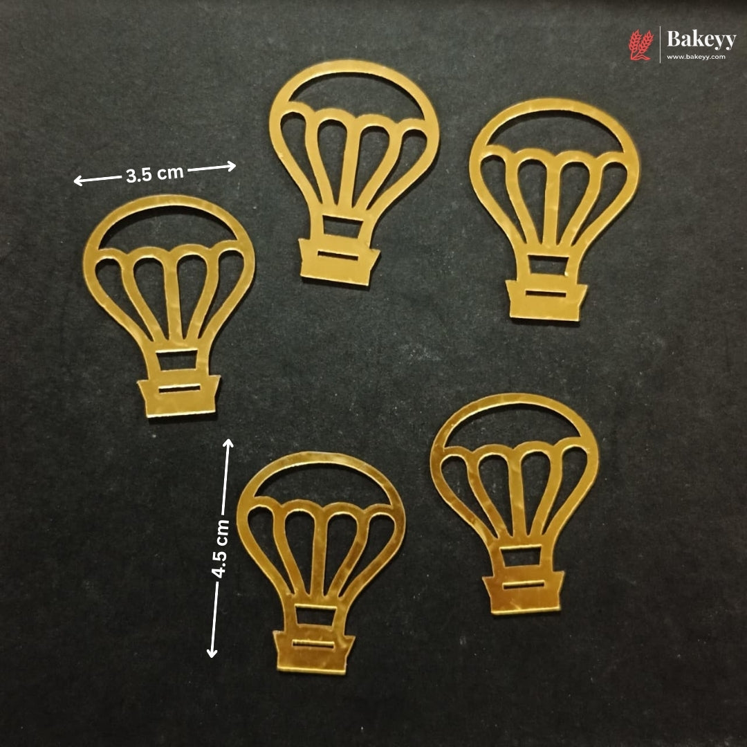 Five gold-colored metal hot air balloon cutouts arranged on a dark textured background, with white dimension arrows and text indicating 3.5 cm width and 4.