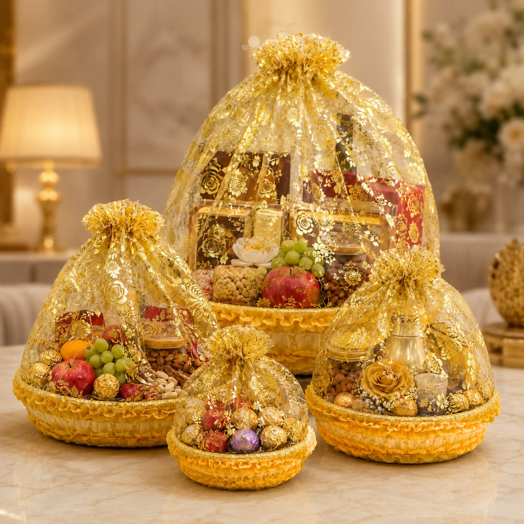 Decorative gift baskets with fruits and flowers under gold netting on a table.