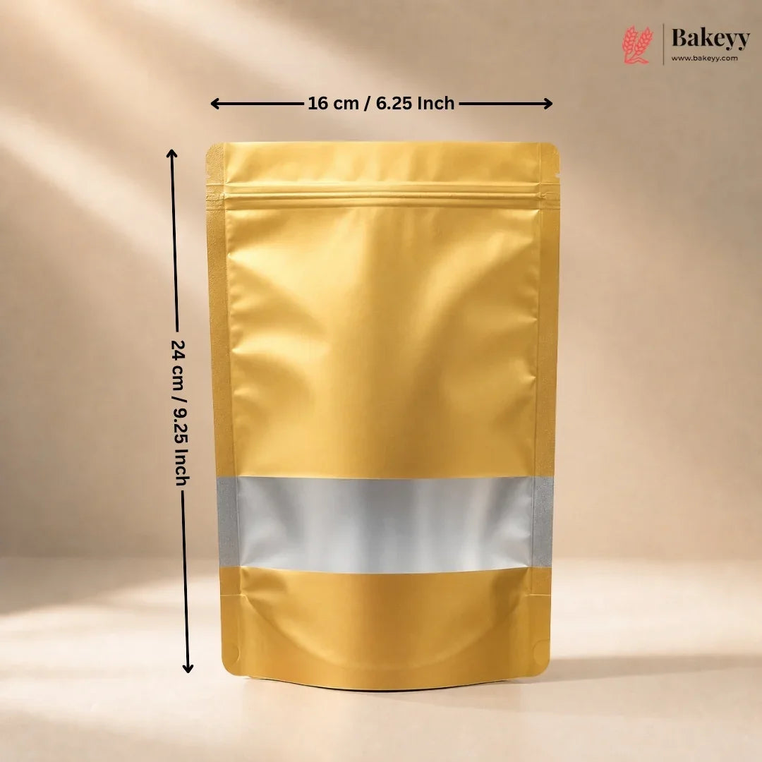 A metallic gold stand-up pouch bag with a reflective silver band across the middle, shown with dimension arrows indicating 16 cm by 24 cm on a beige studio background. A Bakeyy logo appears in the top right.