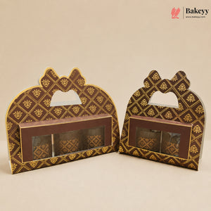Two decorative brown and gold gift boxes with bow-shaped handles and a clear window displaying packaged items, set against a plain beige background. A Bakeyy logo watermark is visible in the top right corner.