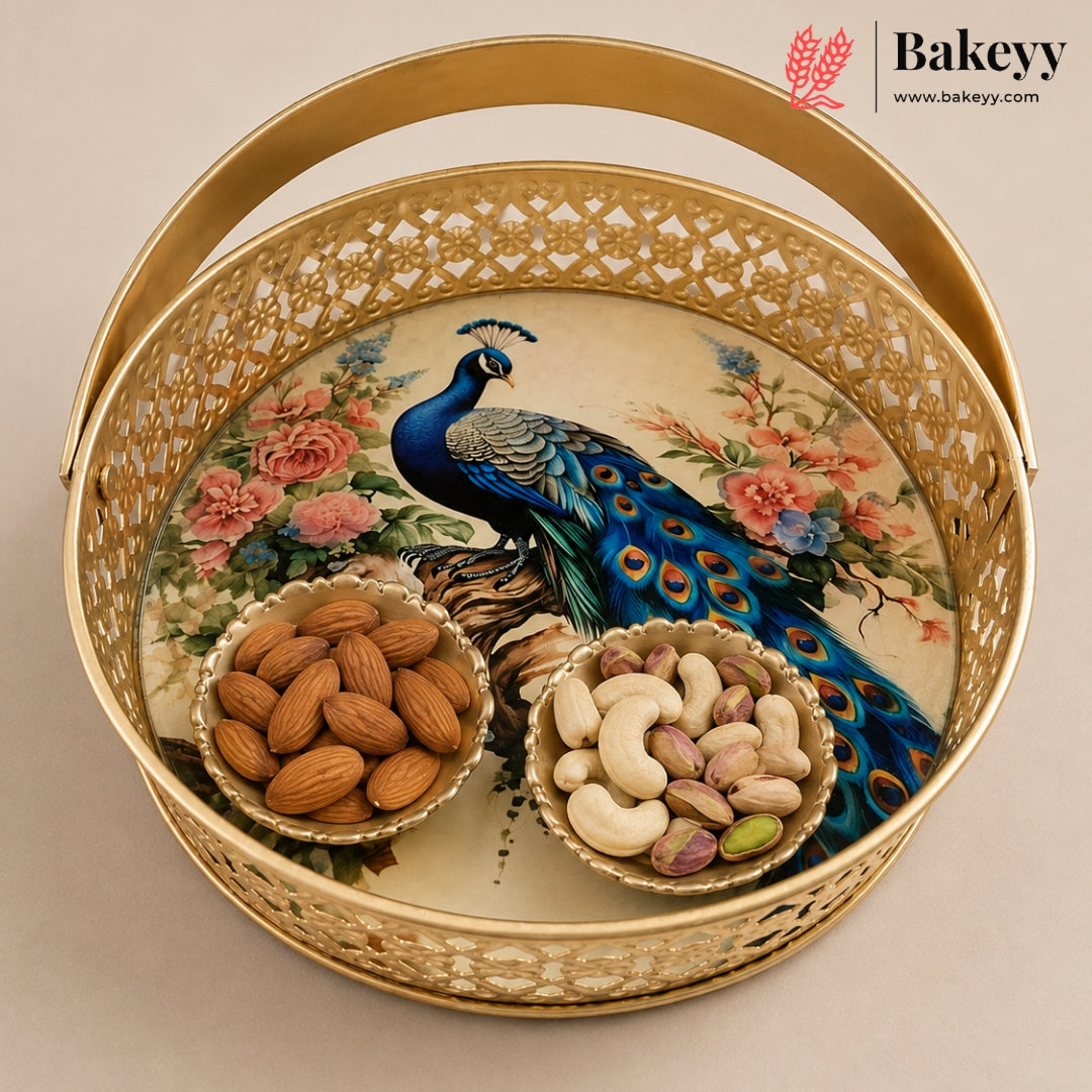 A round gold-toned decorative tray with a cutout lattice edge, featuring a printed peacock and floral design on the inner surface. Two small bowls filled with almonds and cashews sit inside the tray.