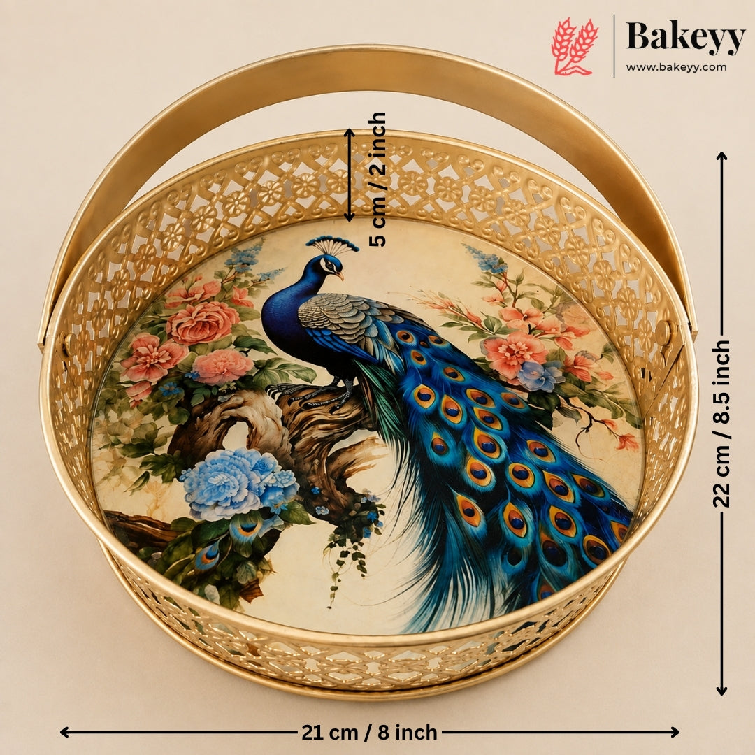 Round gold metal cake pan with a cutout handle and a printed peacock and floral design on the bottom, shown with dimension arrows and text indicating 21 cm diameter and 22 cm height. Bakeyy branding appears in the top right.