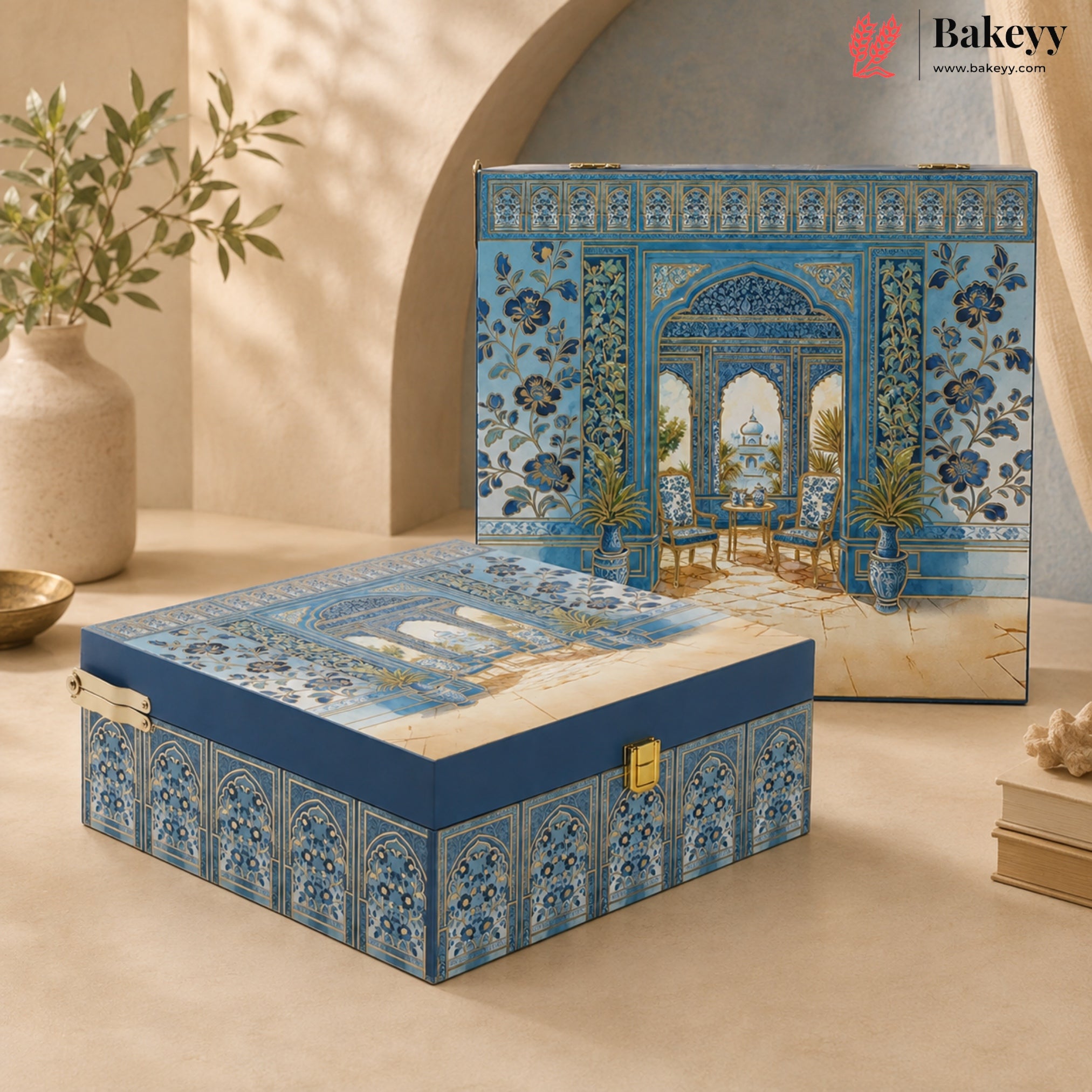 A decorative blue and beige gift box with intricate architectural tile patterns and a gold clasp, shown closed in the foreground with a matching box standing behind it on a warm beige surface.