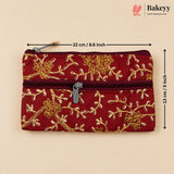 A red quilted zippered pouch with gold floral embroidery, shown on a beige background with dimension lines indicating 22 cm by 13 cm. The Bakeyy logo is visible in the top right corner.