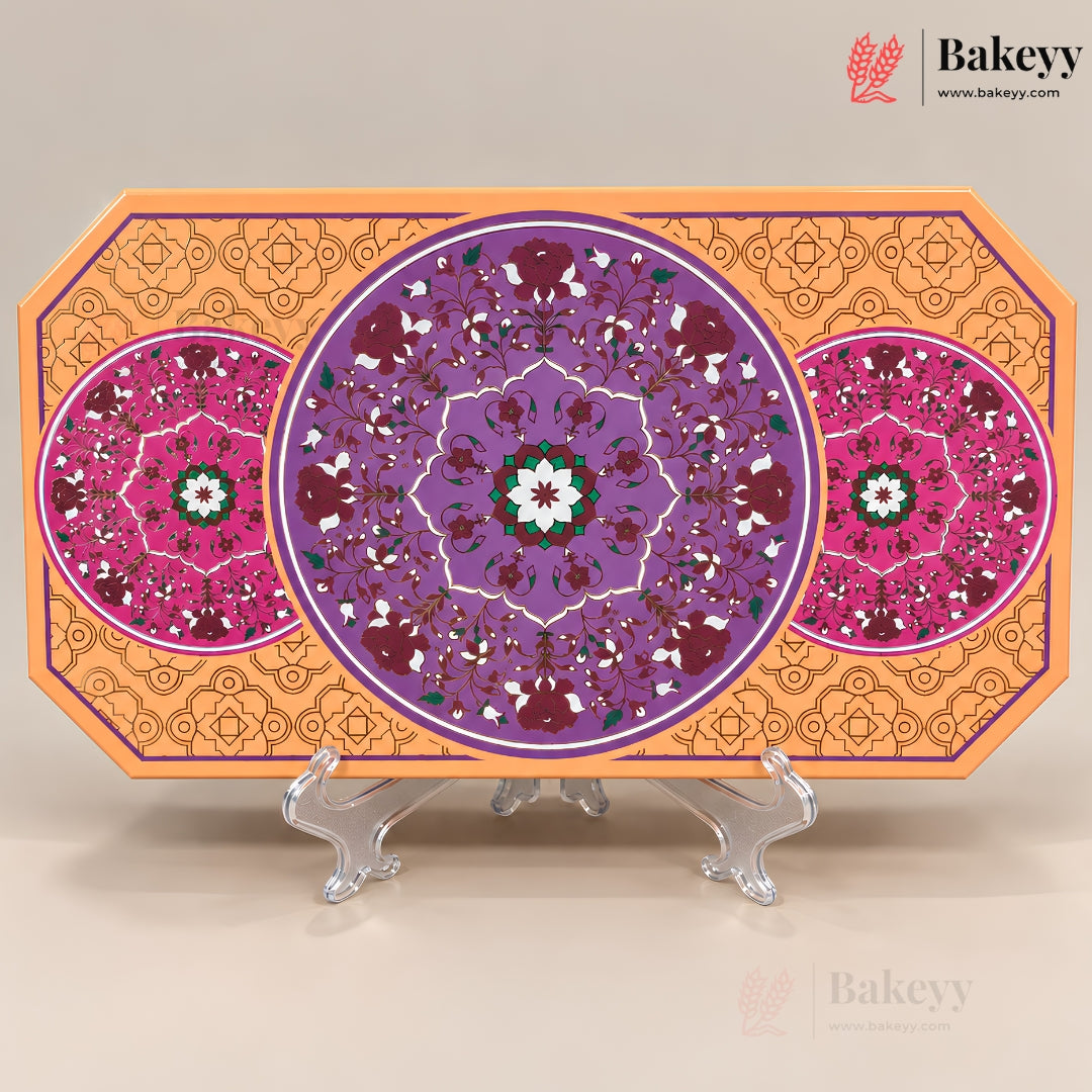 An octagonal decorative tray or board with intricate circular floral mandala patterns in purple, pink, orange, and green, displayed on clear acrylic stands against a light beige background. The Bakeyy brand logo is visible in the top right corner.