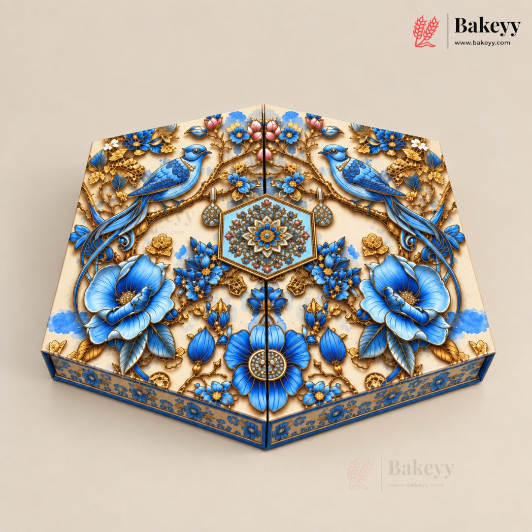 An ornate rectangular cake or pastry box with a highly detailed, 3D floral and bird design. The design features vibrant blue flowers, blue birds, and intricate gold patterns on a cream-colored base, set against a solid beige background.