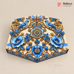 An ornate rectangular cake or pastry box with a highly detailed, 3D floral and bird design. The design features vibrant blue flowers, blue birds, and intricate gold patterns on a cream-colored base, set against a solid beige background.