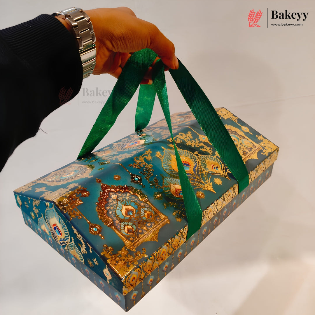 A hand wearing a silver watch holds a decorative teal and gold patterned gift box with green ribbon handles against a plain light background. The Bakeyy logo is visible in the top right corner.