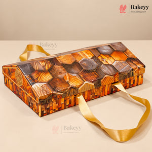 A rectangular wooden gift box with a honeycomb pattern of carved wood panels on top and sides, finished in warm brown and orange tones, with two gold ribbon handles, shown on a beige background.