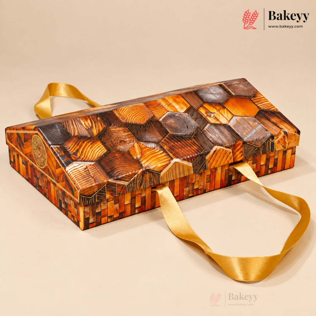 A rectangular wooden box with a honeycomb pattern of wood slices in various shades of brown, featuring a gold satin ribbon handle, set against a solid beige background. The Bakeyy brand logo is visible in the top right corner.