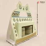 A decorative pastel green and gold ceramic tea or coffee cup holder set with two matching canisters, shown with dimension arrows and labels on a plain beige background. The Bakeyy logo appears in the top right.