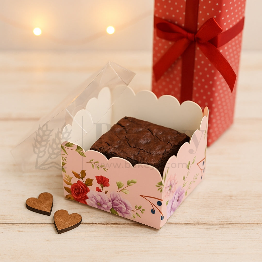 Brownie in a decorative box with floral design, wooden hearts, and a gift box in the background.