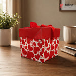 Red gift box with heart patterns on a wooden surface, featuring the Bakeyy brand.