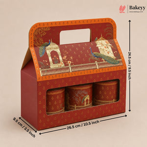 A red and orange decorative gift box with a handle, shown with printed dimensions and arrows indicating its size. The box has a window displaying three matching cylindrical tins with peacock and architectural illustrations.