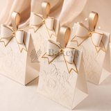 Beige gift bags with gold ribbons on a beige background