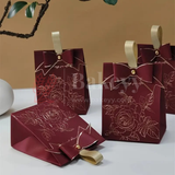 Red gift boxes with floral designs and gold ribbons on a beige background