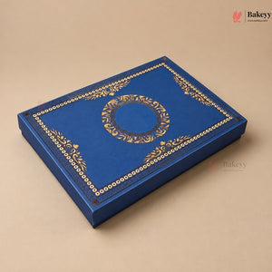 A rectangular blue bakery gift box with ornate gold foil detailing, including a central circular motif and decorative borders, shown on a solid beige background.