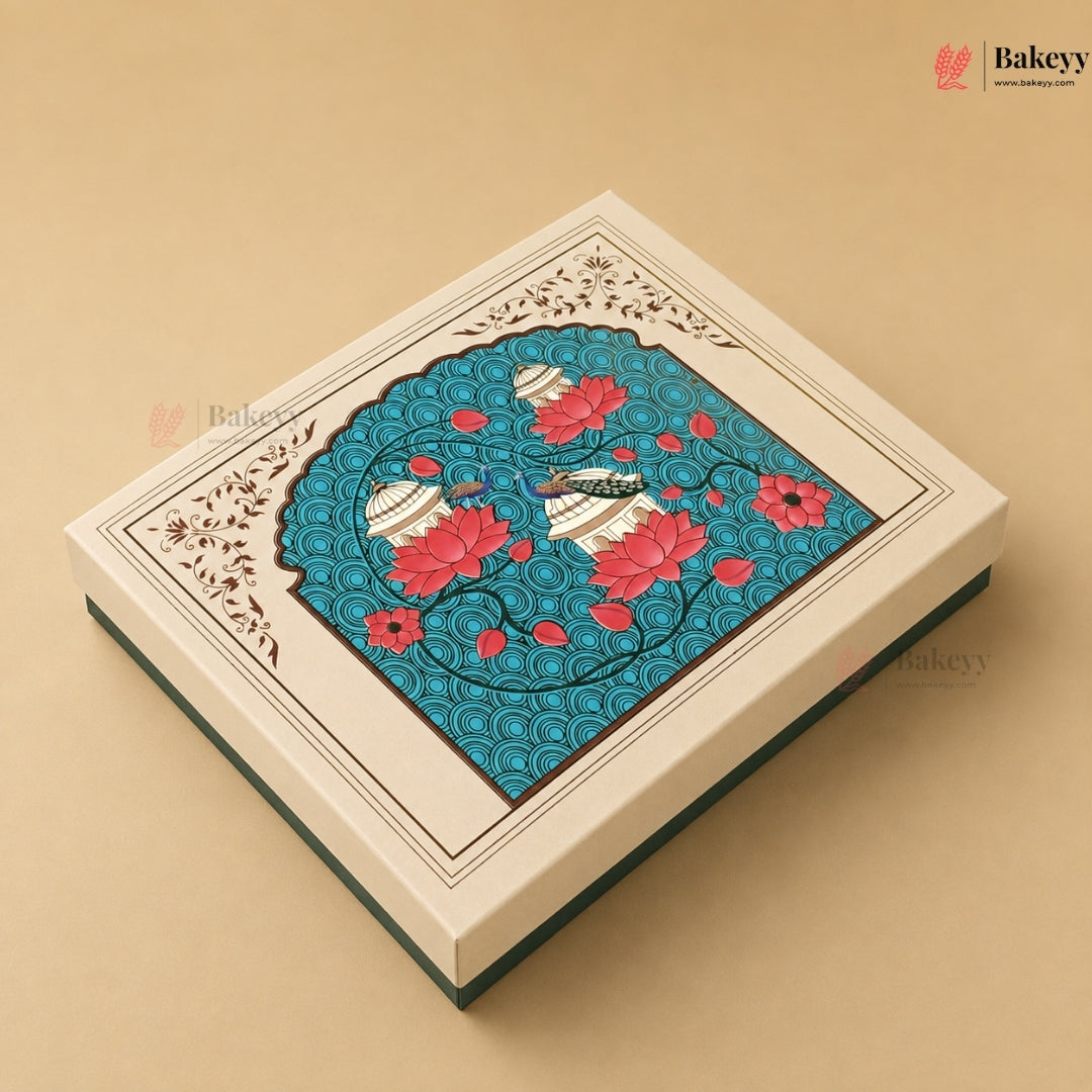 An ornate rectangular gift box with a cream-colored lid featuring a detailed central illustration of a peacock surrounded by pink lotus flowers on a turquoise background, set against a solid beige backdrop.