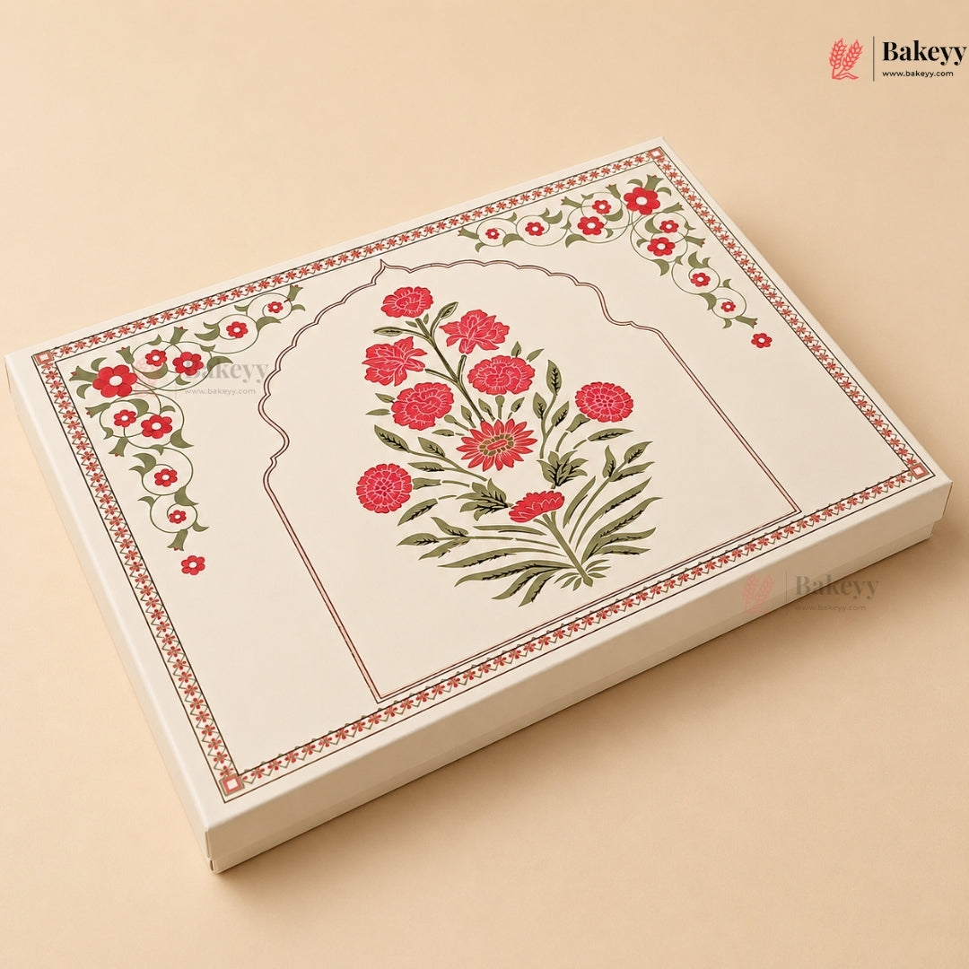 A rectangular cream-colored bakery box with traditional Indian floral patterns, featuring a central arch design with red flowers and green leaves, set against a solid beige background.