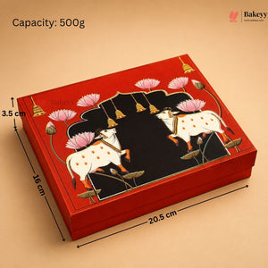 A rectangular red gift box with a decorative lid featuring two white cows, pink lotus flowers, and a black central panel, shown on a beige background with printed dimensions and capacity text.